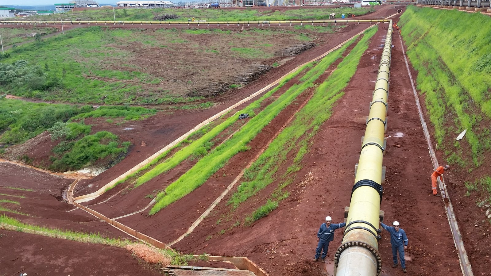 Adutora em PRFV de grande diâmetro assentada em campo aberto, com dois profissionais junto ao flange