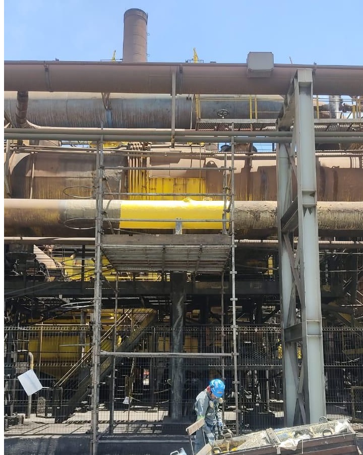 Tubulação industrial de grande porte com trecho reforçado em manutenção