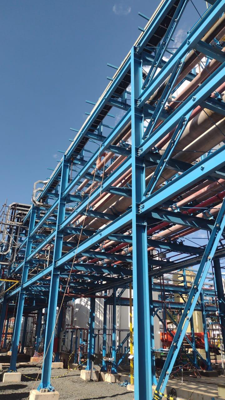 Pipe rack de estrutura metálica azul com tubulações de processo montadas pela Brito Engenharia